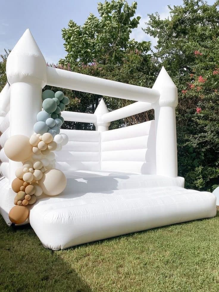 White bounce house with neutral balloon garland in Miami