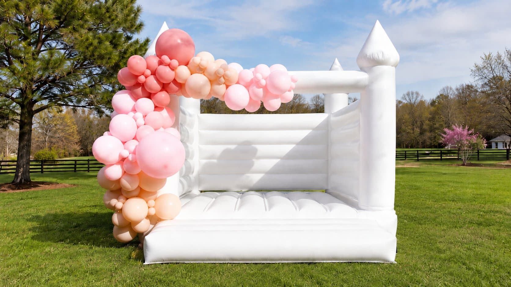 White Bounce House with Pink and Peach Balloons White bounce house with pink and peach balloon garland for a Miami event rental